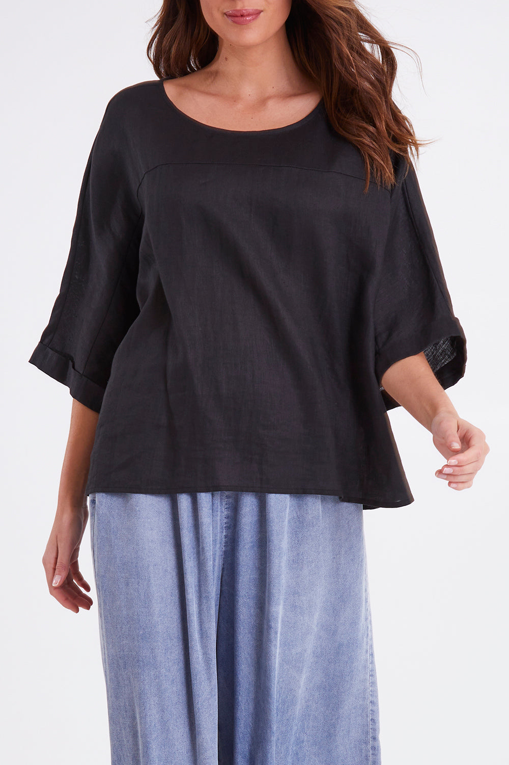 Model Madeline wearing size OneSize of the Studio Relaxed Top in colour Ebony (Black), from the front, cropped image