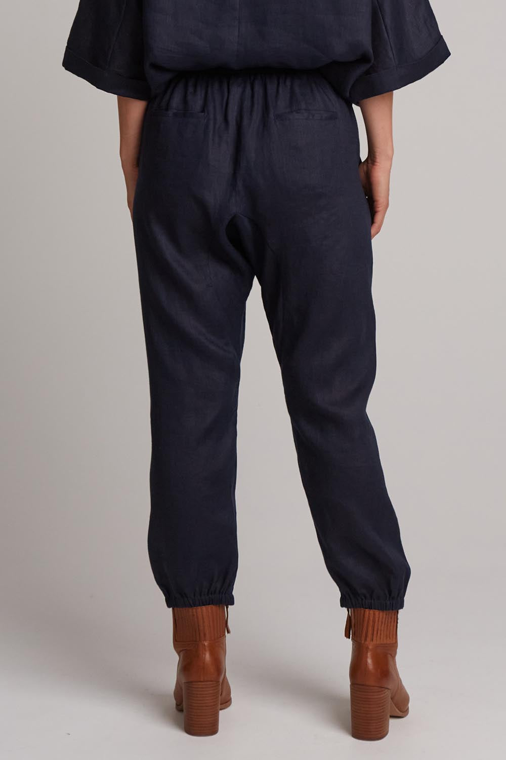 A model wearing the Studio Relaxed Linen Pant in colour Navy (Blue), from the back