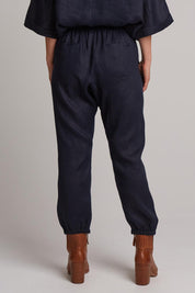 A model wearing the Studio Relaxed Linen Pant in colour Navy (Blue), from the back