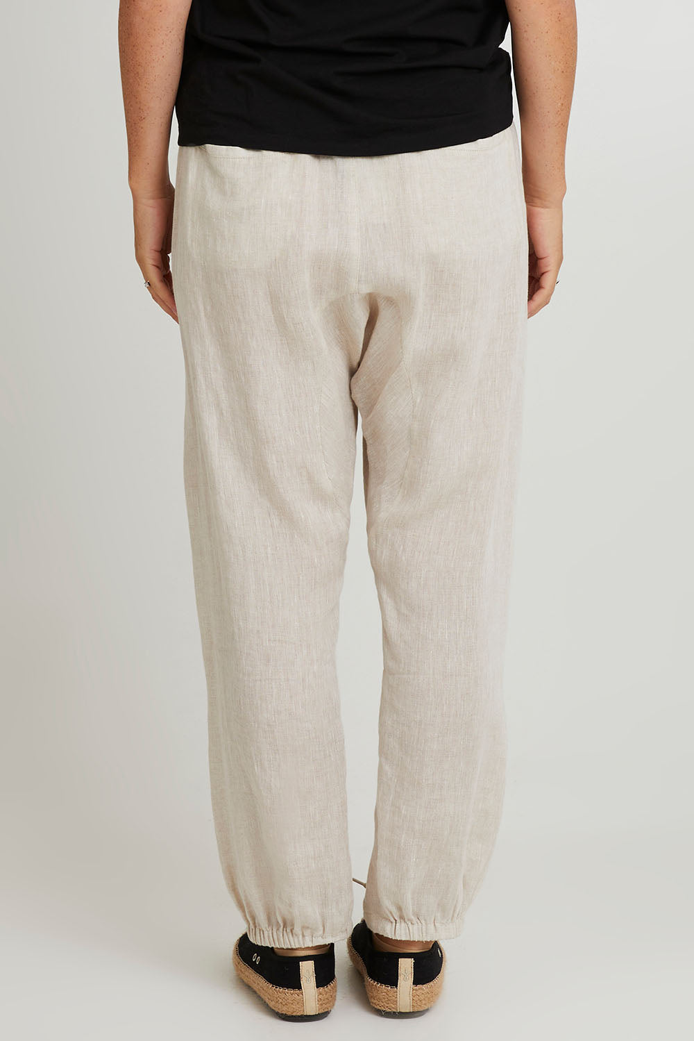 Model Katie wearing size S of the Studio Relaxed Linen Pant in colour Tusk, from the back