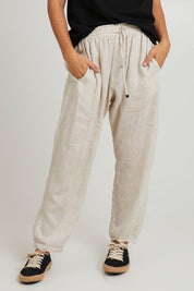Model Katie wearing size S of the Studio Relaxed Linen Pant in colour Tusk, from the front, cropped image