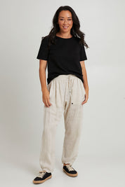 Model Katie wearing size S of the Studio Relaxed Linen Pant in colour Tusk, from the front, showing the whole outfit