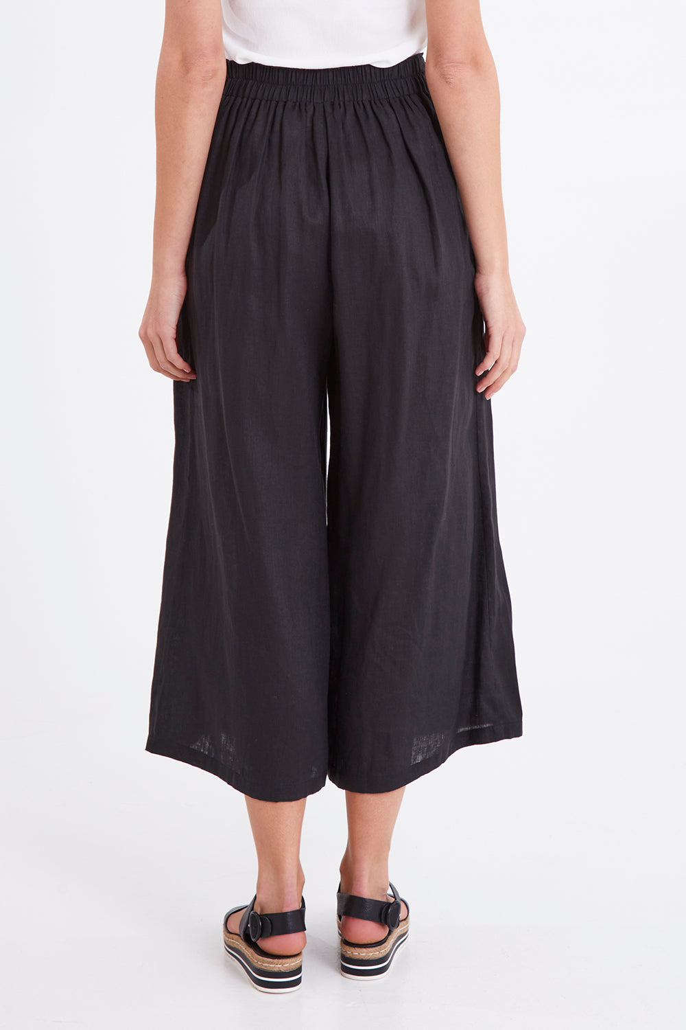 Model Madeline wearing size S of the Studio Crop Pant in colour Ebony (Black), from the back