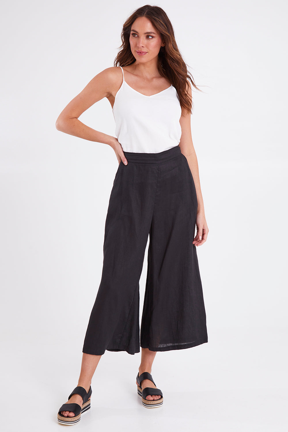 Model Madeline wearing size S of the Studio Crop Pant in colour Ebony (Black), from the front, showing the whole outfit