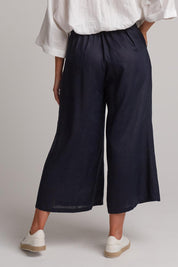 A model wearing the Studio Crop Pant in colour Navy (Blue), from the back