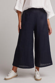 A model wearing the Studio Crop Pant in colour Navy (Blue), from the front, cropped image