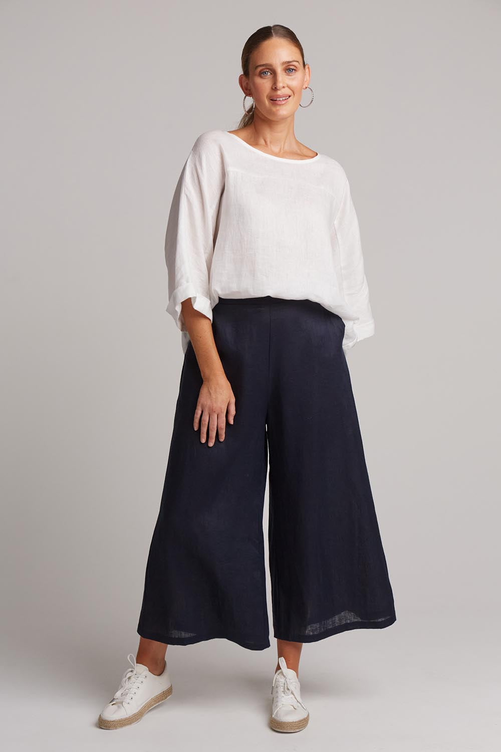 A model wearing the Studio Crop Pant in colour Navy (Blue), from the front, showing the whole outfit