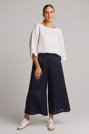 A model wearing the Studio Crop Pant in colour Navy (Blue), from the front, showing the whole outfit