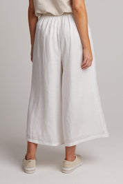 A model wearing the Studio Crop Pant in colour Salt (White), from the back