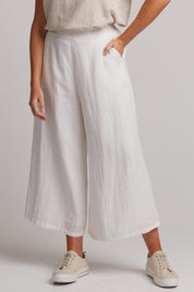 A model wearing the Studio Crop Pant in colour Salt (White), from the front, cropped image