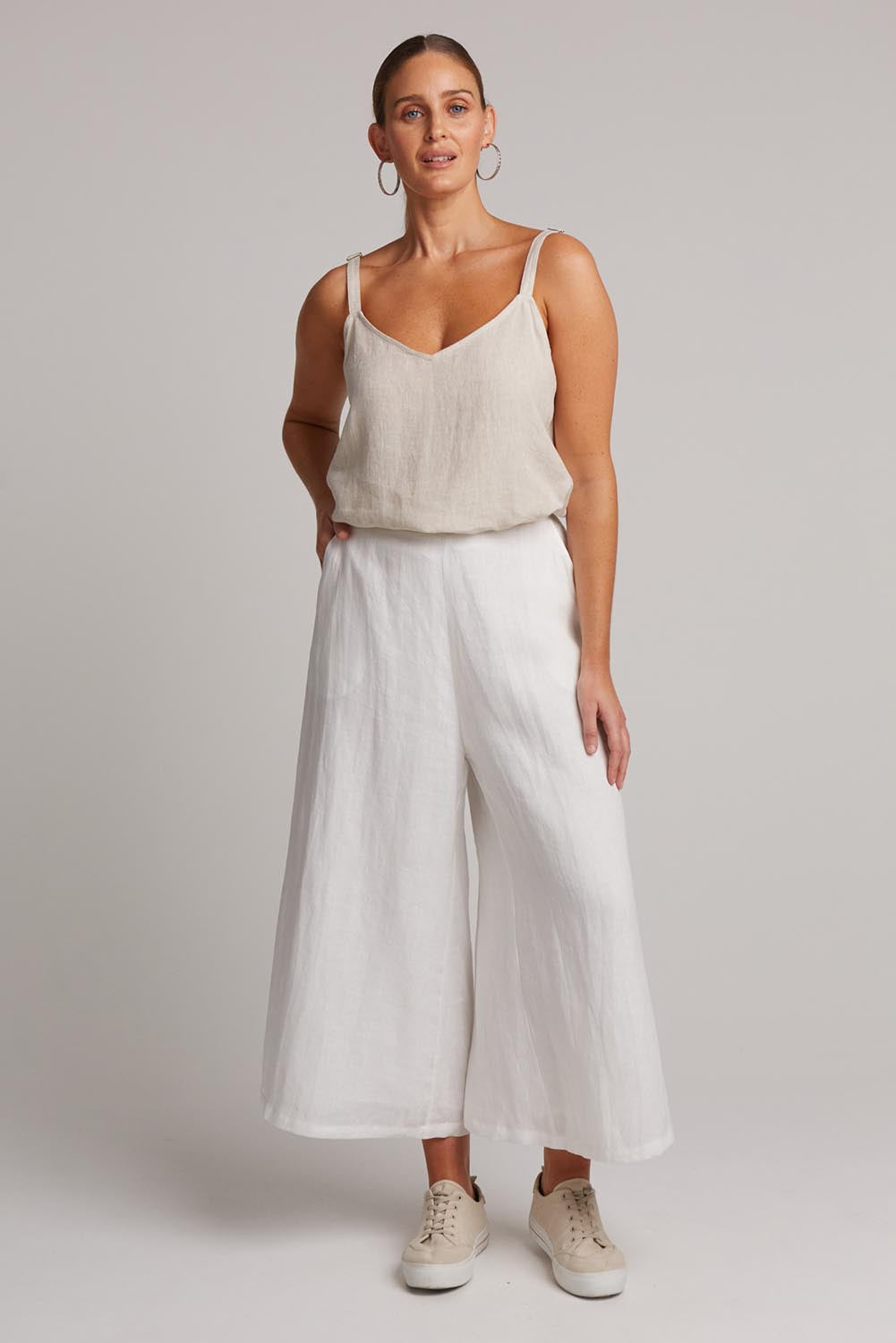 A model wearing the Studio Crop Pant in colour Salt (White), from the front, showing the whole outfit