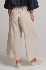 A model wearing the Studio Crop Pant in colour Tusk, from the back