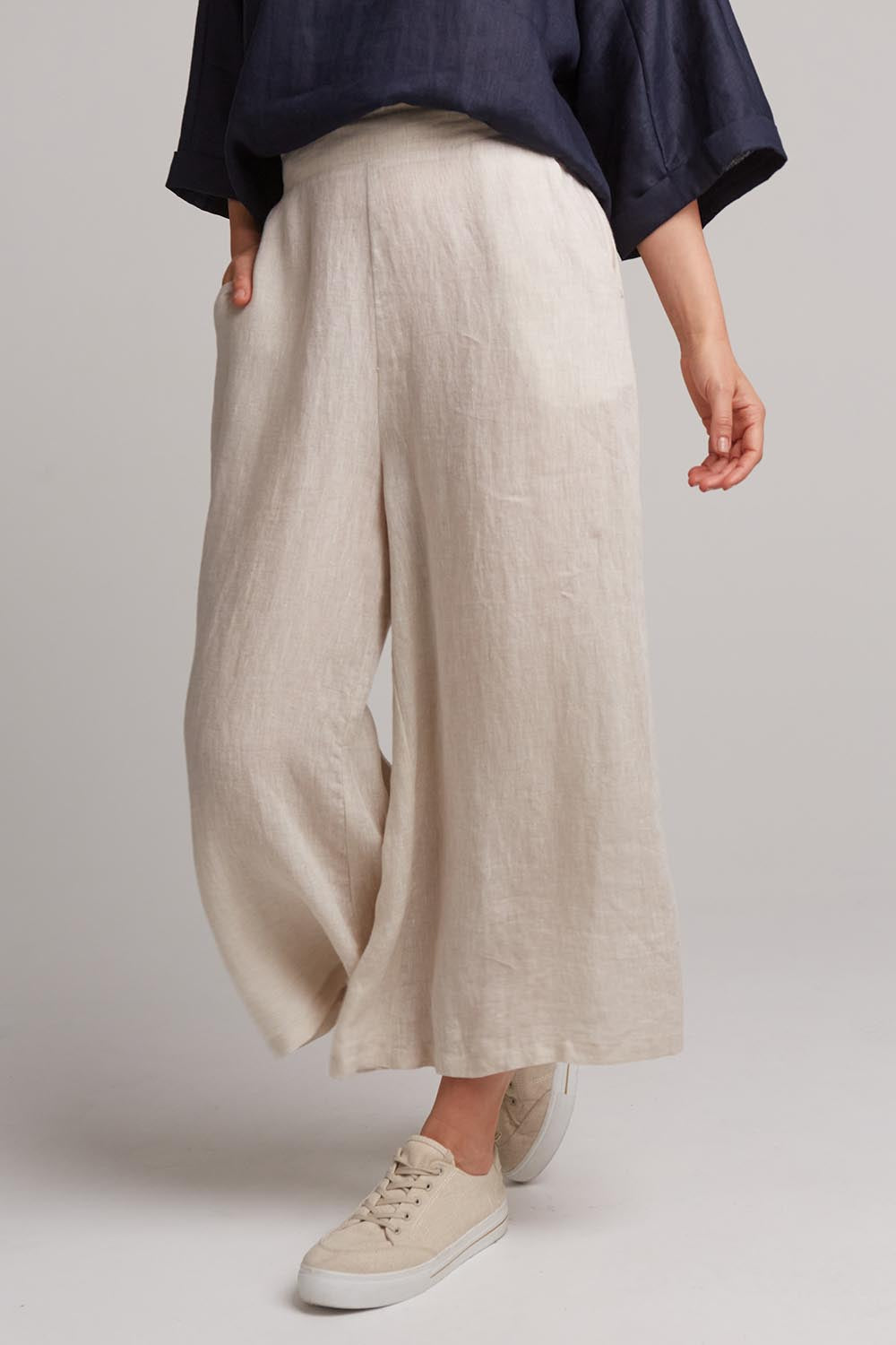 A model wearing the Studio Crop Pant in colour Tusk, from the front, cropped image