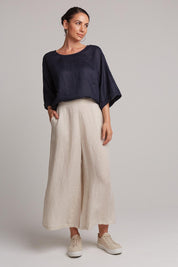 A model wearing the Studio Crop Pant in colour Tusk, from the front, showing the whole outfit
