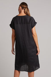 A model wearing the Studio Linen Dress in colour Ebony (Black), from the back