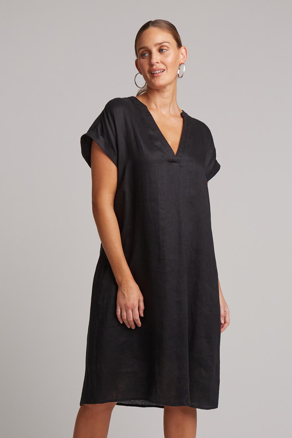 A model wearing the Studio Linen Dress in colour Ebony (Black), from the front, cropped image