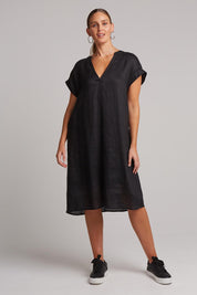 A model wearing the Studio Linen Dress in colour Ebony (Black), from the front, showing the whole outfit