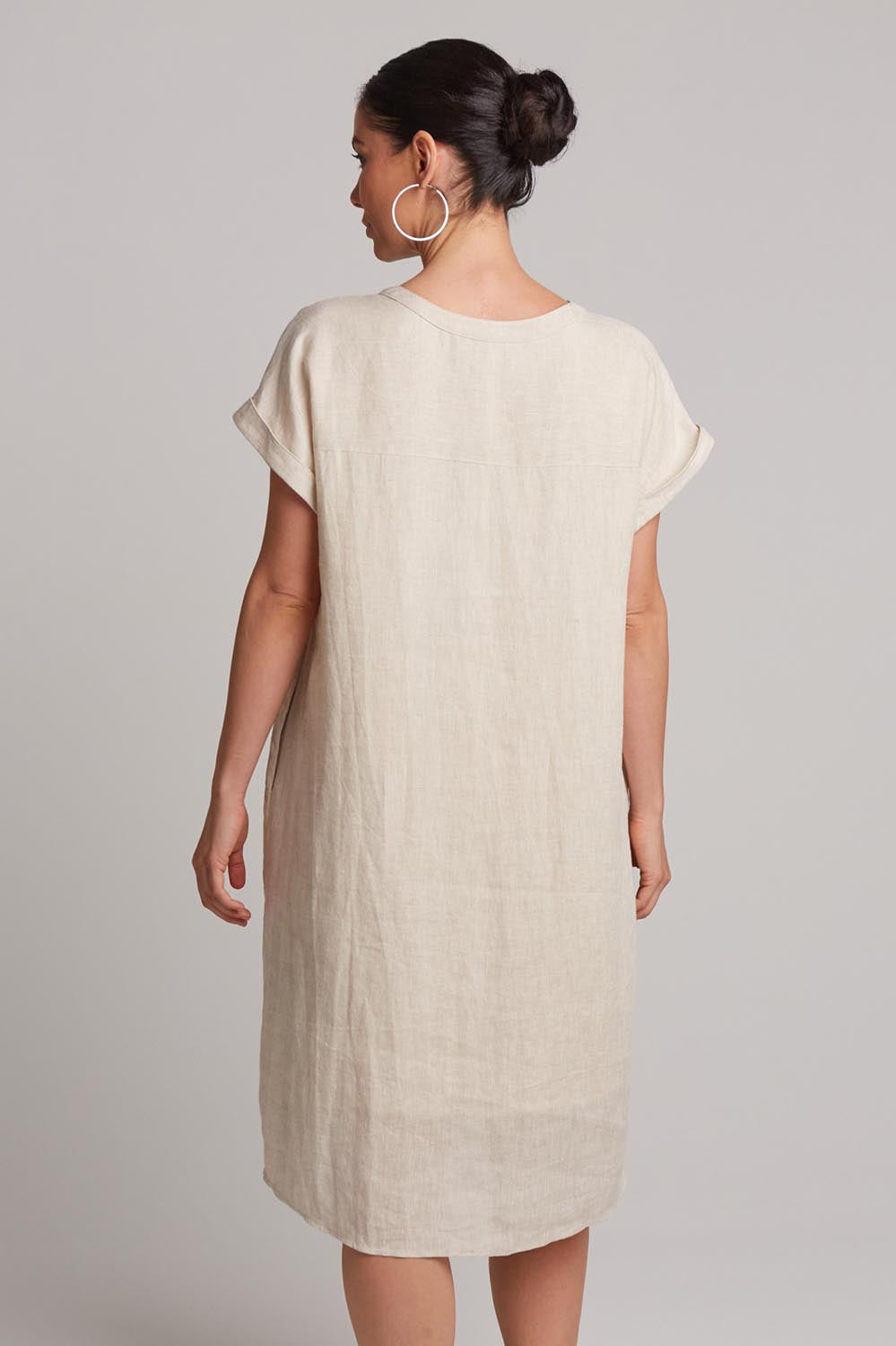 A model wearing the Studio Linen Dress in colour Tusk, from the back