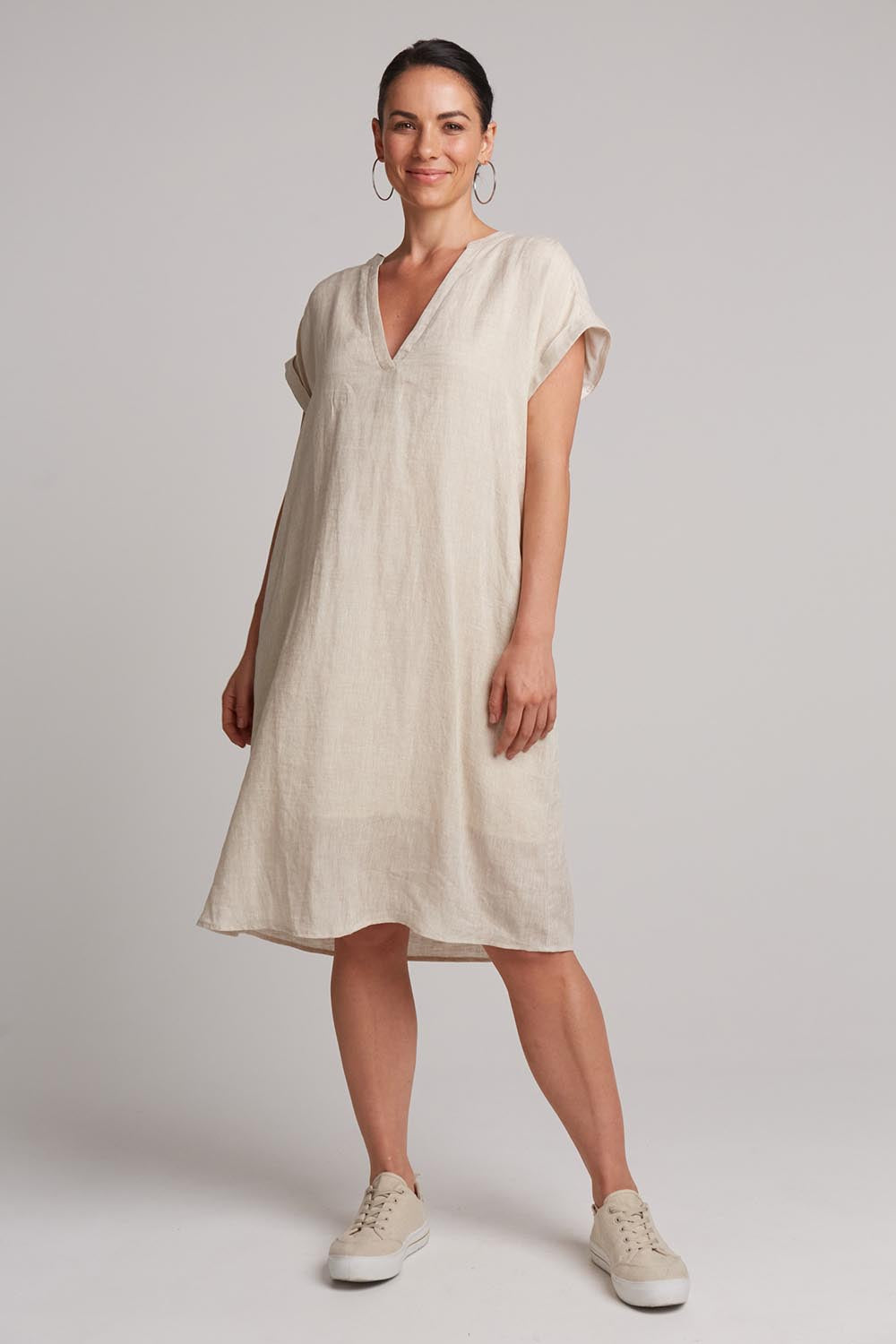 A model wearing the Studio Linen Dress in colour Tusk, from the front, showing the whole outfit