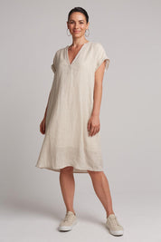 A model wearing the Studio Linen Dress in colour Tusk, from the front, showing the whole outfit