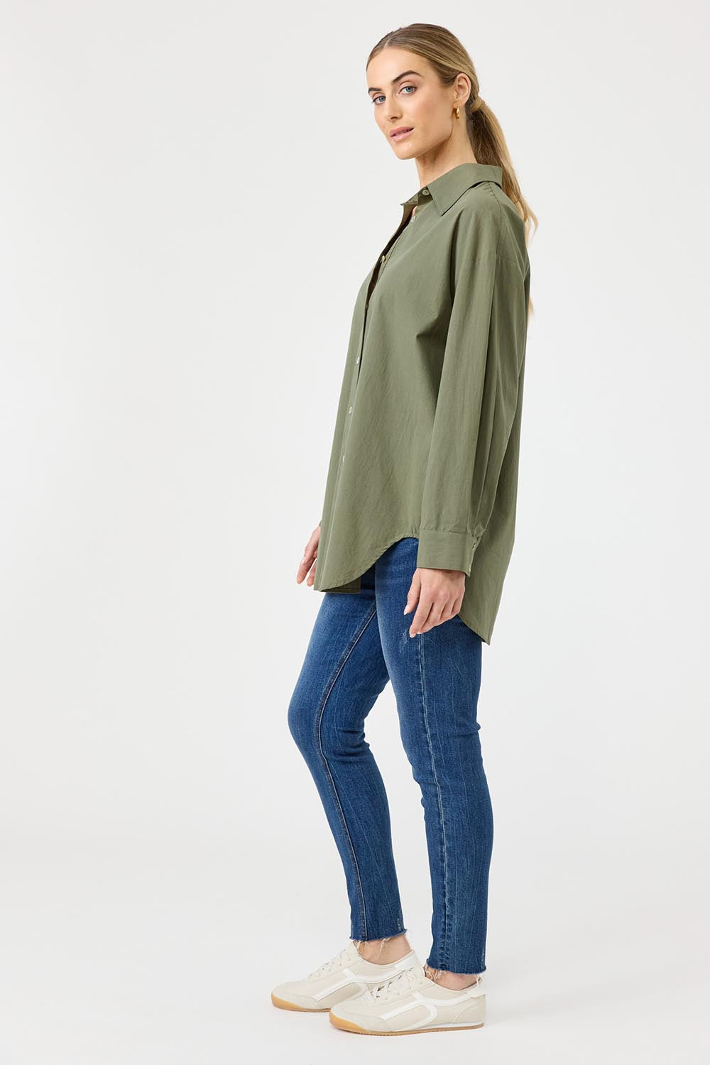 A model wearing the Studio Oversize Cotton Shirt in colour Khaki (Green), from the front, showing the whole outfit