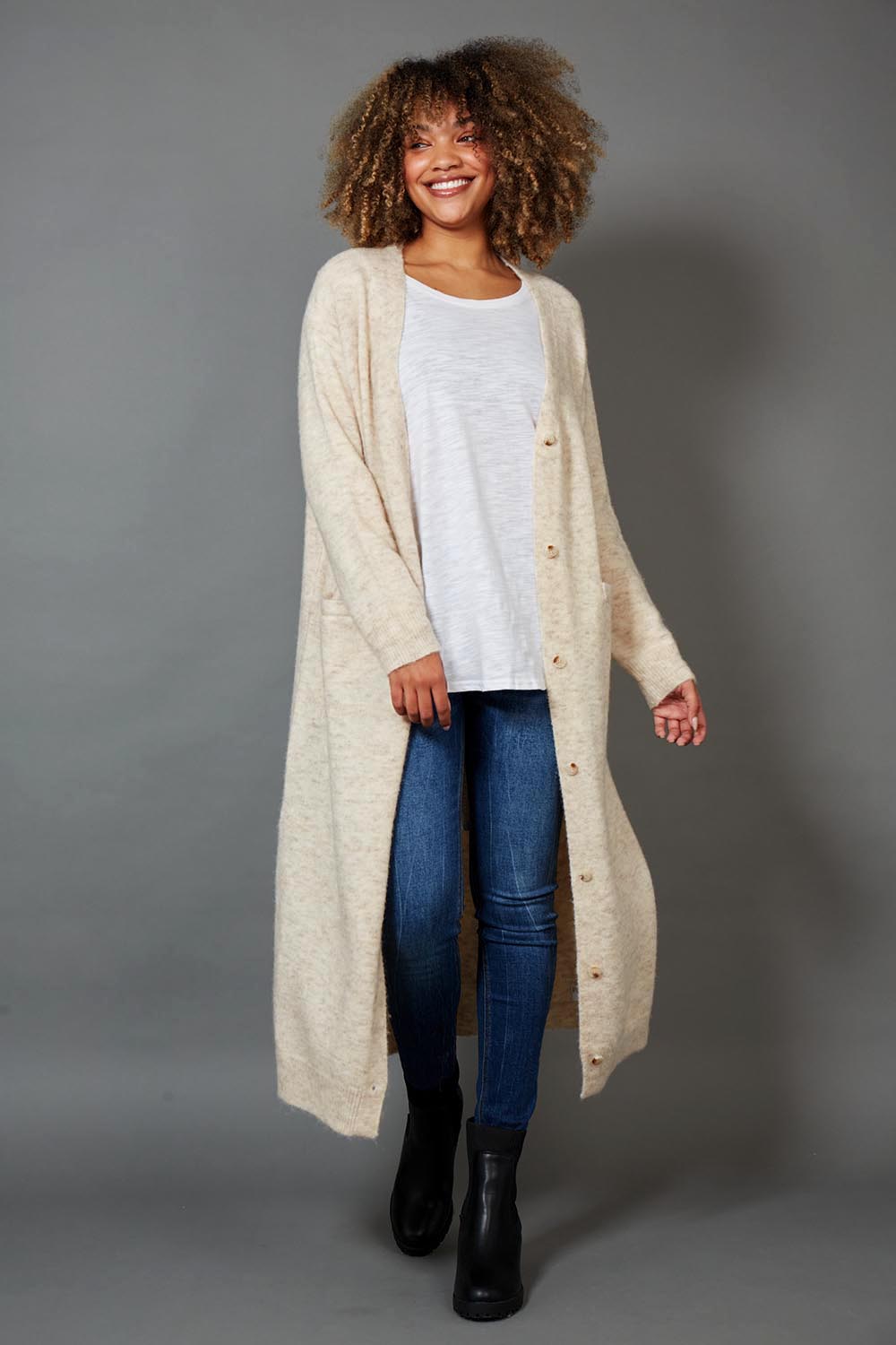 A model wearing the Kinsella Cardigan in colour Tusk, from the front, showing the whole outfit