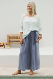 A model wearing the Elan Pant in colour Denim (Blue), from the front, showing the whole outfit