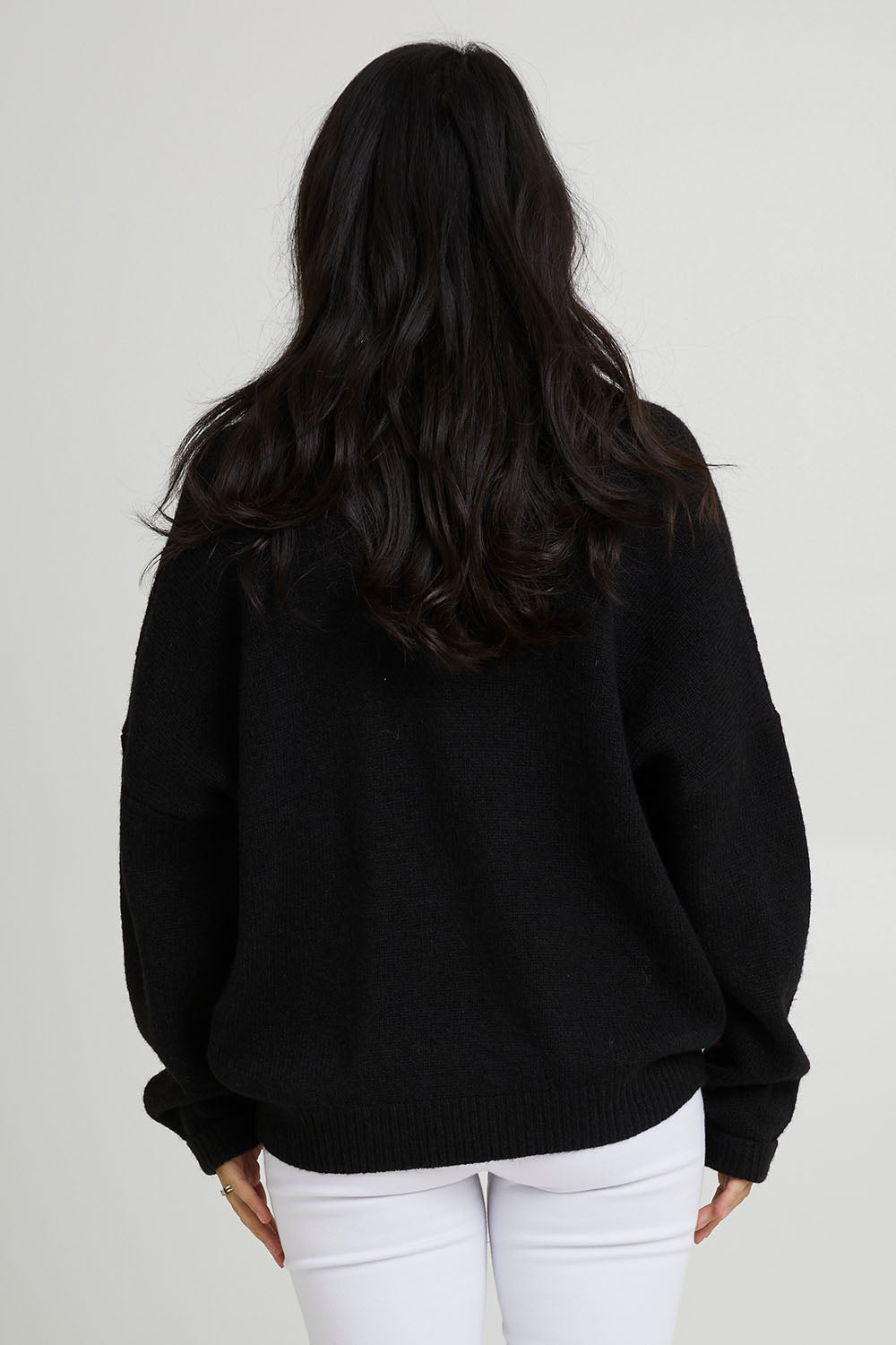 Model Katie wearing size S of the Parrl Crossover Knit in colour Ebony (Black), from the back