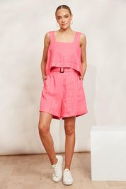 A model wearing the Halcyon Linen Shorts in colour Musk (Pink), from the front, showing the whole outfit
