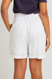 Model Olivia wearing size S of the Halcyon Linen Shorts in colour Opal (White), from the back