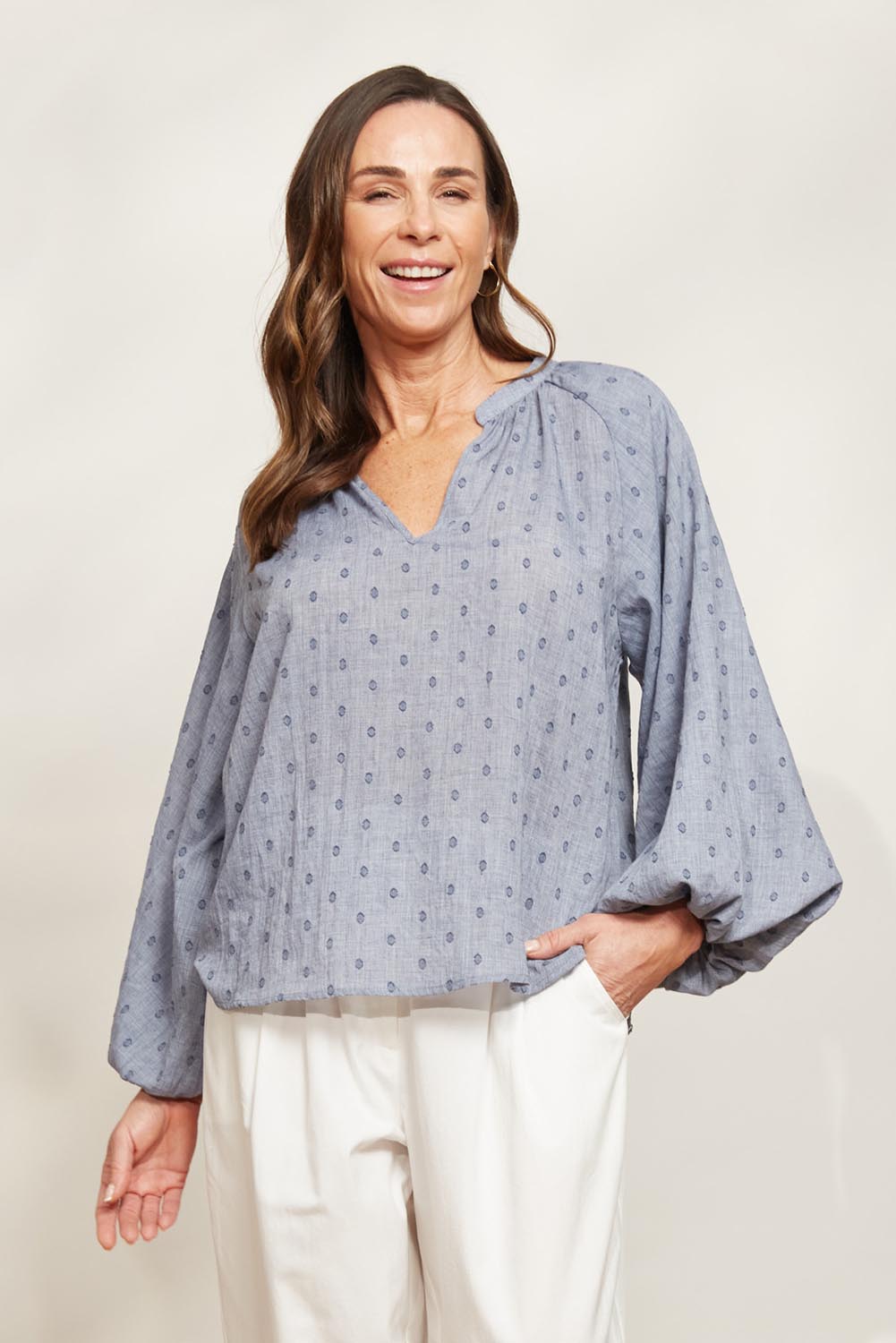 A model wearing the Zephyr Blouse in colour Nevada (Blue), from the front, showing the whole outfit