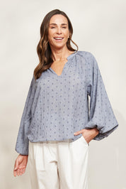 A model wearing the Zephyr Blouse in colour Nevada (Blue), from the front, showing the whole outfit