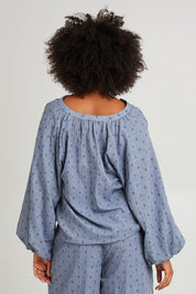 Model Olivia wearing size S of the Zephyr Blouse in colour Nevada (Blue), from the back