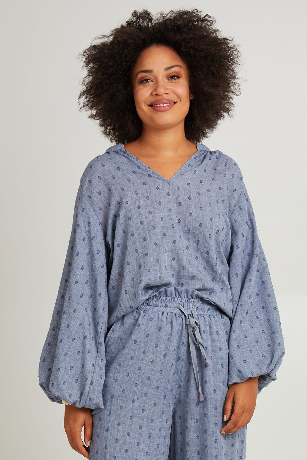 Model Olivia wearing size S of the Zephyr Blouse in colour Nevada (Blue), from the front, cropped image