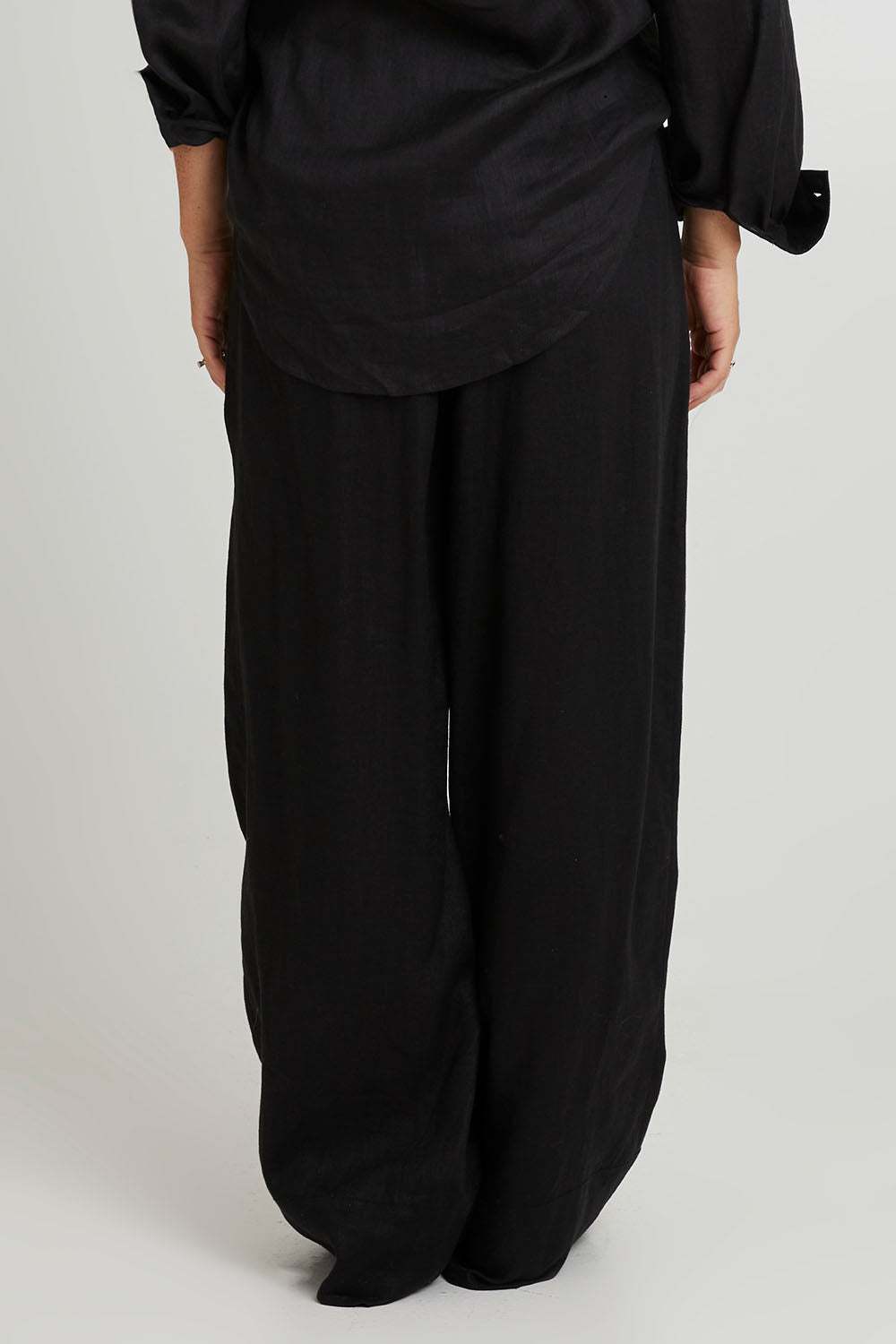 Model Katie wearing size S of the Studio Linen Pant in colour Ebony (Black), from the back