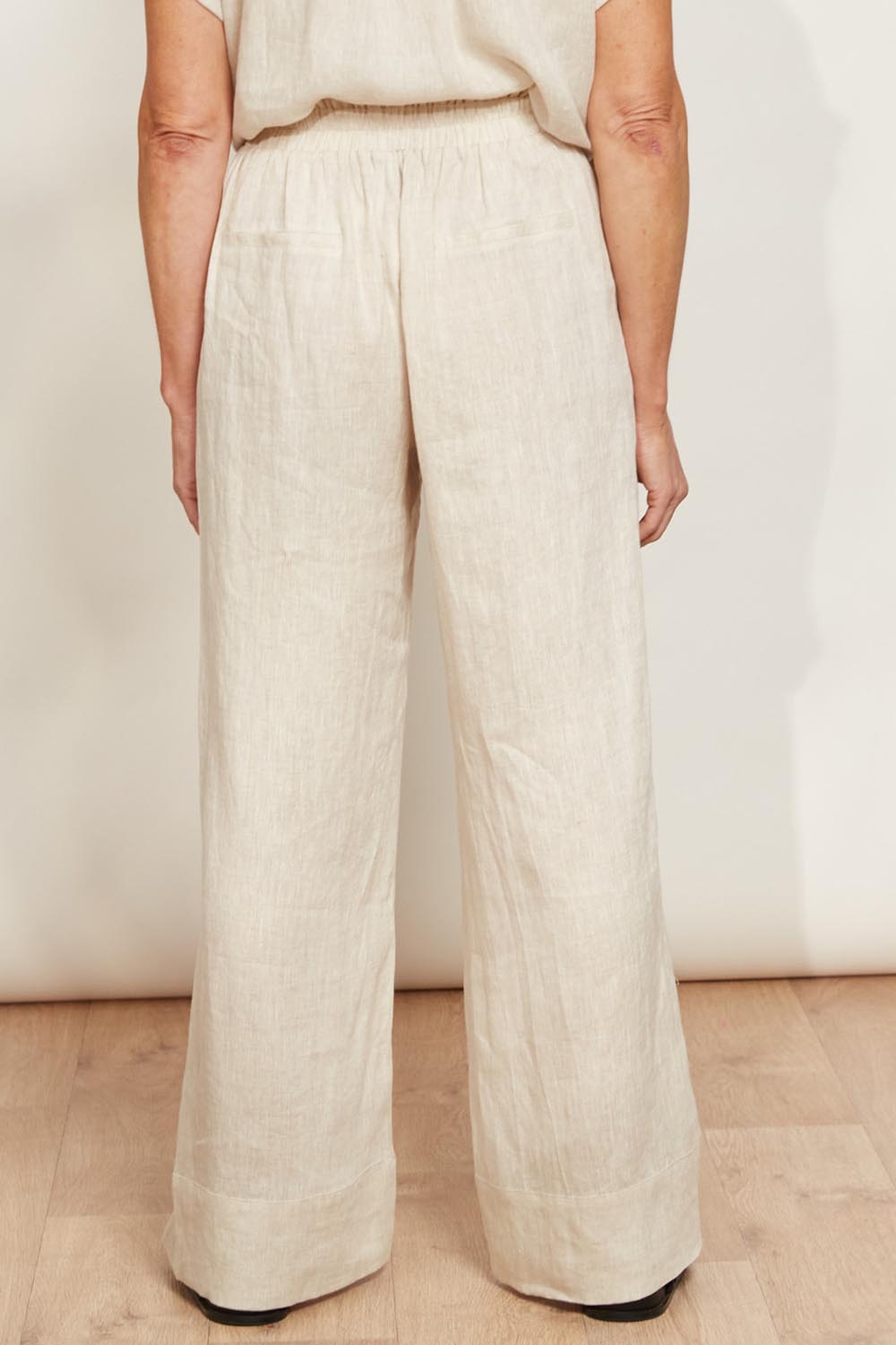 A model wearing the Studio Linen Pant in colour Tusk, from the back
