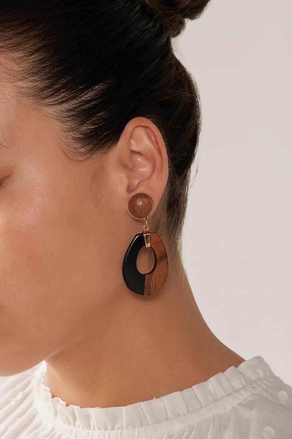 A model wearing the Cay Earring in colour Blackstrip (Black), from the front, cropped image