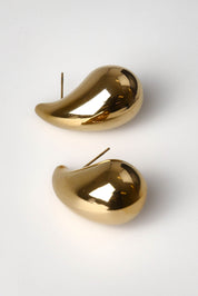A model wearing the Halcyon Earring in colour Gold (Metallics), from the front, showing the whole outfit