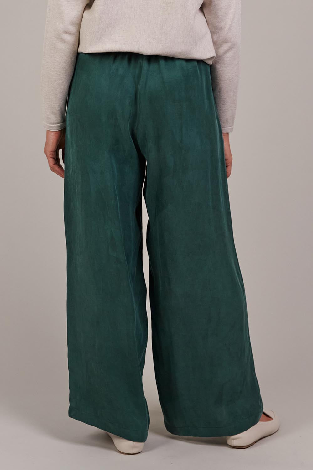 A model wearing the Eden Cupro Blend Pant in colour Aventurine (Green), from the back