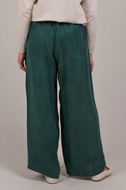 A model wearing the Eden Cupro Blend Pant in colour Aventurine (Green), from the back
