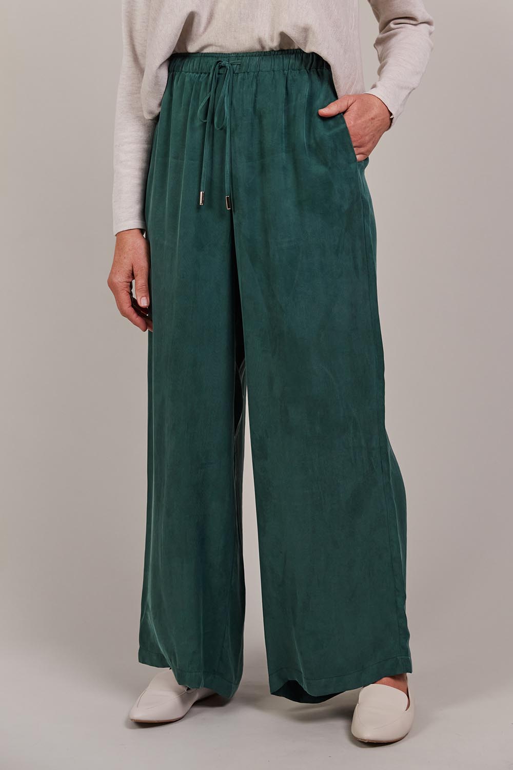 A model wearing the Eden Cupro Blend Pant in colour Aventurine (Green), from the front, cropped image