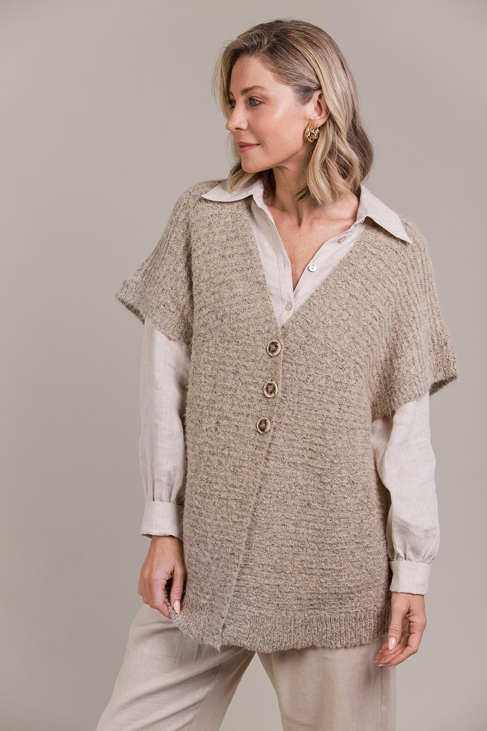 A model wearing the Folie Button Vest in colour Oat, from the front, cropped image