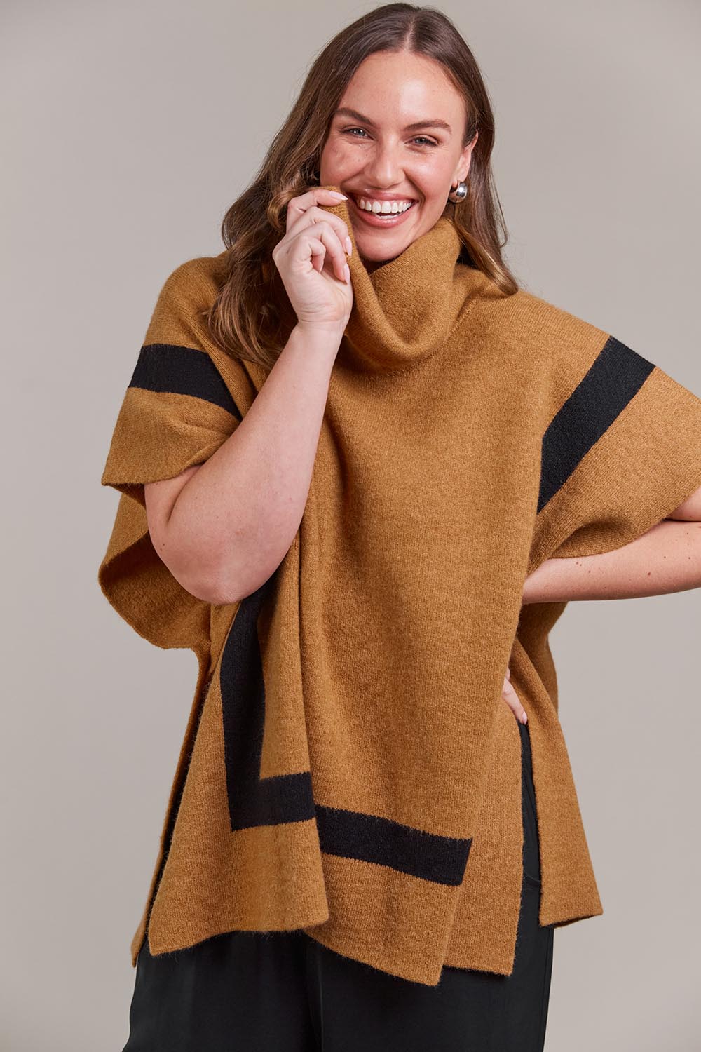 A model wearing the Avino Poncho in colour Tobacco, from the front, cropped image