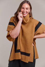 A model wearing the Avino Poncho in colour Tobacco, from the front, cropped image