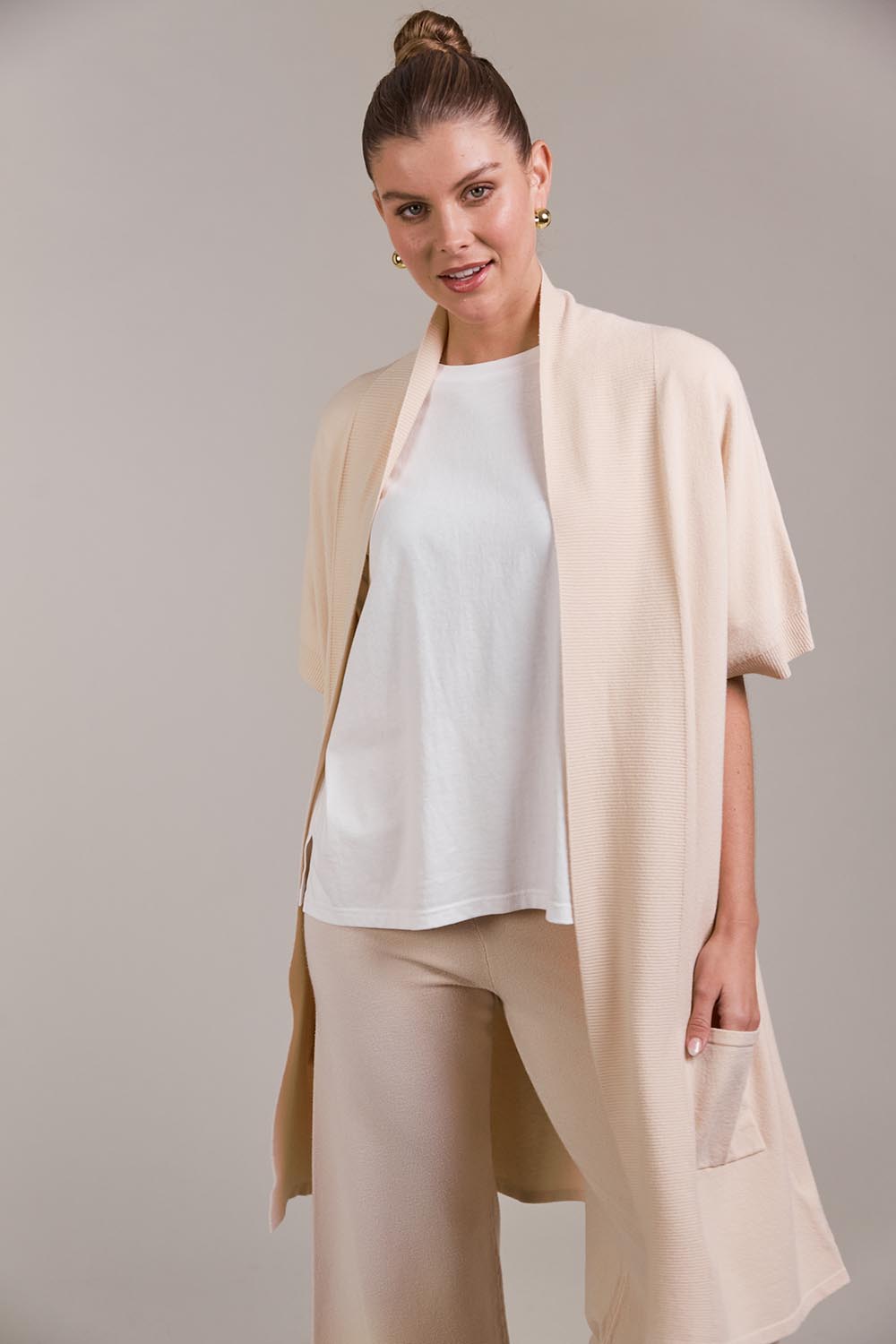 A model wearing the Palmer Vest Cardigan in colour Ecru, from the front, cropped image