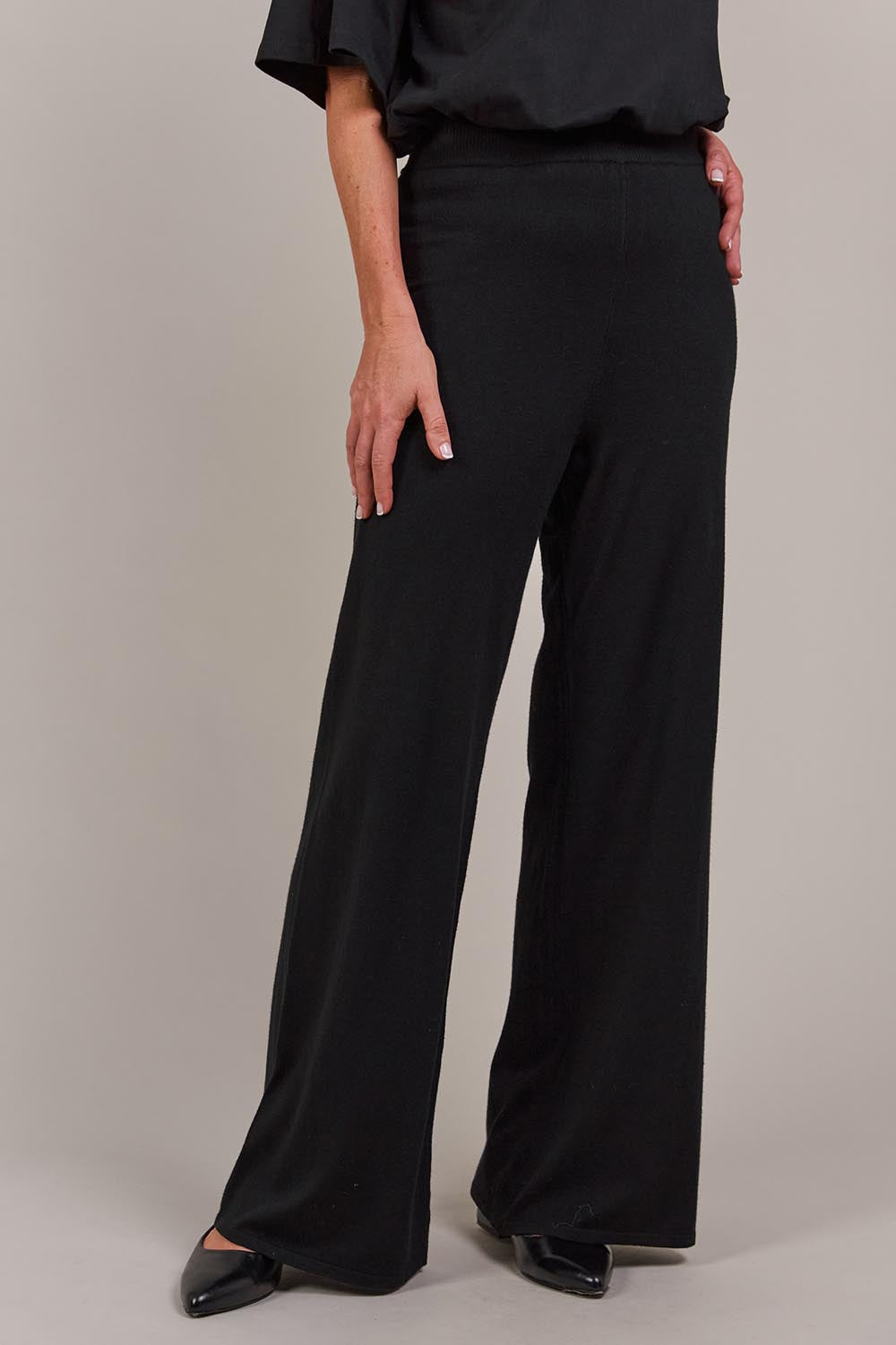 A model wearing the Palmer Knit Pant in colour Black (Black), from the front, cropped image