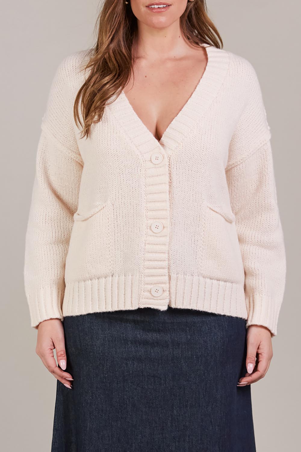 A model wearing the Katana Cardigan in colour Ecru, from the front, cropped image