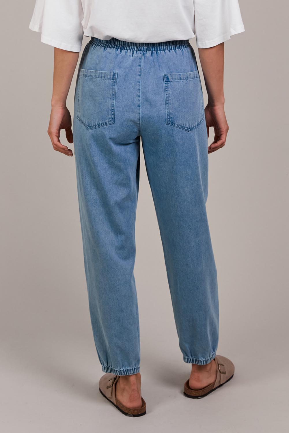A model wearing the Pepi Relaxed Denim Pant in colour Denim (Blue), from the back