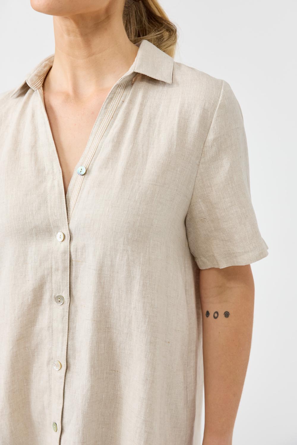A model wearing the Studio Linen Short Shirt Dress in colour Dune, from the front, cropped image
