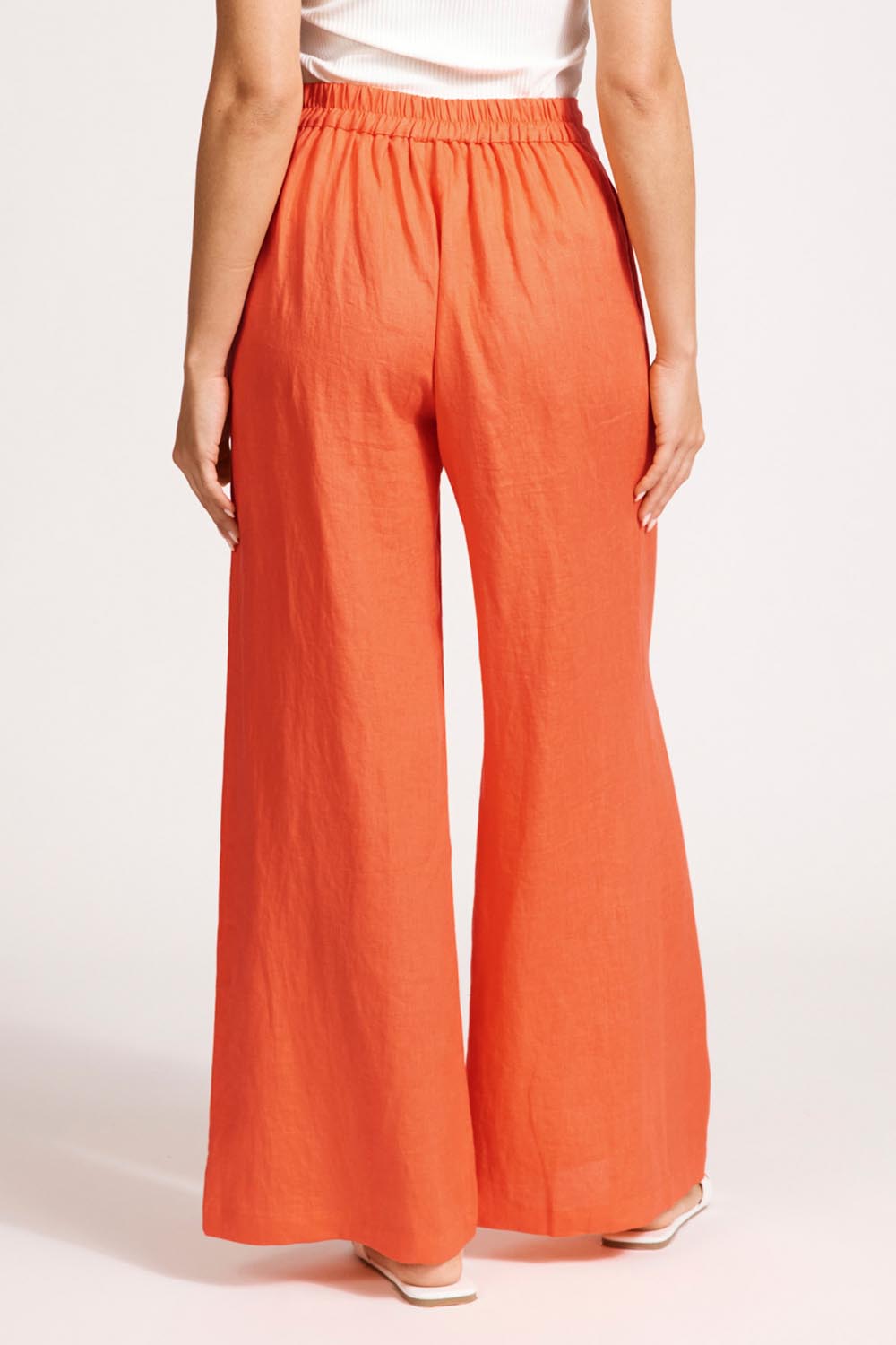 A model wearing the Miranar Linen Palazzo Pant in colour Coral (Red), from the back